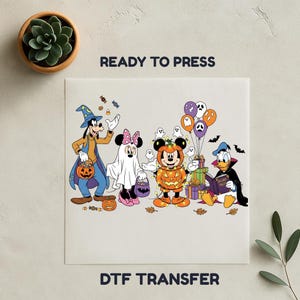 May include: DTF transfer featuring Disney characters in Halloween costumes. Goofy in a witch hat, Minnie Mouse as a ghost, Mickey Mouse in a pumpkin costume, and Donald Duck reading a book. The text "READY TO PRESS" and "DTF TRANSFER" are also visible.