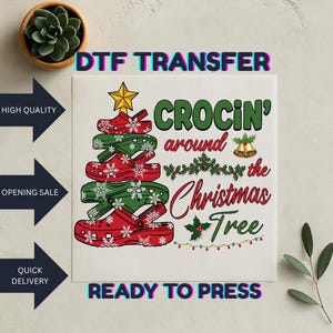 May include: A DTF transfer design with a Christmas tree made of red and green clogs with snowflake details. The text says "CROCIN' around the Christmas Tree". Includes a gold star, bells, and holly.