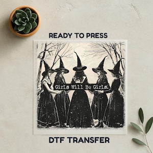 May include: A black and white DTF transfer featuring six witches in long dresses and pointed hats, holding a banner that reads "Girls Will Be Girls." The image is set against a backdrop of bare trees.