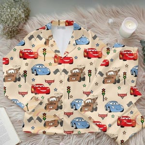 Zoom into dreamland with this Cars Satin Pajama Set, featuring Lightning McQueen, Mater, and Sally against a playful beige racing backdrop. Perfect for Pixar fans, kids, and parents who love cozy, matching sleepwear with a fun race day vibe 🏆🚗💨
