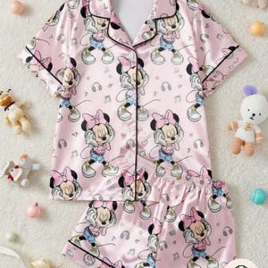Turn bedtime into Minnie's personal dance party with this super cozy custom pajamas set featuring Minnie Mouse rocking big headphones – dancing with sassy smiles, arms up, surrounded by floating music notes, colorful swirls, hearts & stars on a soft pastel pink background – pure girly, musical Disney joy perfect for family matching, Disney movie nights, kids' bedtime stories, or repping your inner "Minnie DJ" energy!