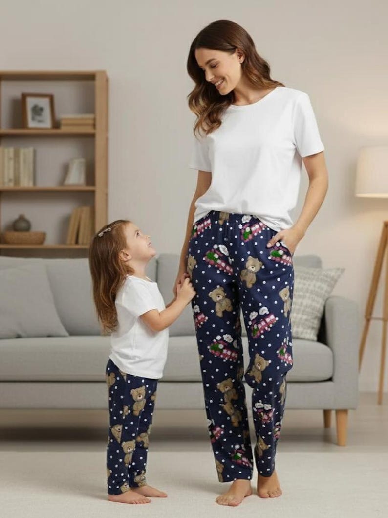 Cute navy pajama pants featuring an all-over print of teddy bears, pink toy trains with “rumi Choo Choo” text, and playful white polka dots. Made from soft, lightweight fabric, these pants are perfect for cozy loungewear or bedtime comfort.