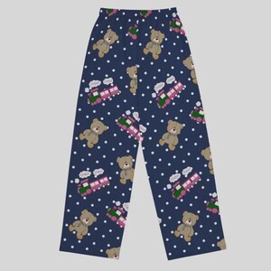 May include: Navy blue pajama pants with a repeating pattern of teddy bears, toy trains, and white polka dots. The bears are tan with green scarves, and the trains are pink and green. The pants have a relaxed fit.