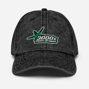 May include: A black, vintage-style baseball cap with a curved brim. The cap features a green and white embroidered logo that reads "3000s Hien dragon" with a stylized design. The cap has a distressed look.