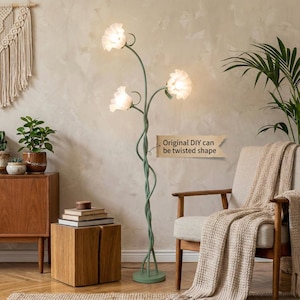 May include: A green floor lamp with three flower-shaped lampshades. The lamp has a twisted stem design and a round base. The text on the image says "Original DIY can be twisted shape". The lamp is in a room with a wooden cabinet, a chair, and a plant.