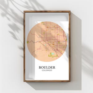 Könnte beinhalten: Gerahmter Druck mit einer kreisförmigen Karte von Boulder, Colorado, in Beige-, Braun- und Grüntönen. Die Karte zeigt Straßen und geografische Merkmale. Der Name der Stadt und des Bundesstaates sind darunter in einer modernen Schrift gedruckt.