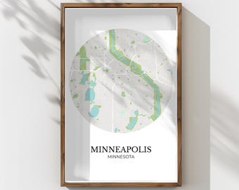 May include: Framed print featuring a circular map of Minneapolis, Minnesota, with green and blue accents. The map is set against a white background, and the frame is a natural wood color. The city name is displayed in a clean, modern font.