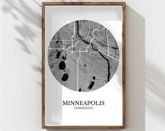 May include: Framed black and white map print of Minneapolis, Minnesota. The city map is circular, with roads and waterways detailed in grayscale. The print is in a wooden frame, with the city name and state printed below the map.