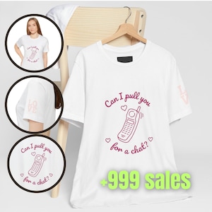 May include: A white short-sleeved t-shirt featuring a pink line-art graphic of a vintage mobile phone with the text Can I pull you for a chat? and small hearts. The sleeve displays the word LOVE in light pink lettering on the side.