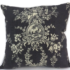 May include: A black and white patterned throw pillow with a floral design. The pillow has a white background with black floral patterns and a central medallion with a bird design.