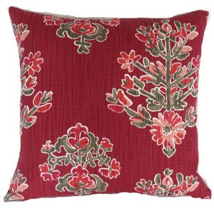 May include: A square decorative pillow with a deep red background and a repeating floral pattern in shades of red, pink, and olive green. The pillow has a textured appearance and a white border.
