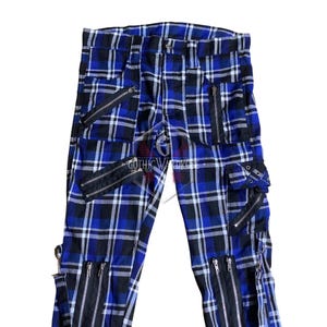 May include: Blue and black plaid pants with multiple black zippers and pockets. The pants feature a classic plaid pattern with a modern, edgy design. The text "GOTHIC WARDROBE" is visible.