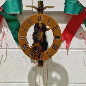 May include: A wooden cuckoo clock with a circular face featuring Roman numerals. The clock has a decorative design and hanging weights. The clock is mounted on a white wall.