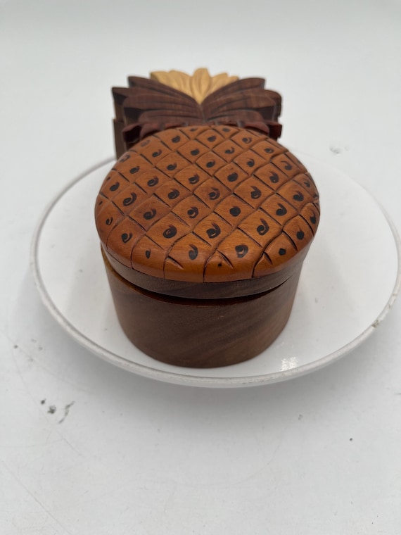 A hand-carved wooden pineapple that's secretly a puzzle box with a hidden compartment — you have to figure out the mechanism to get inside.