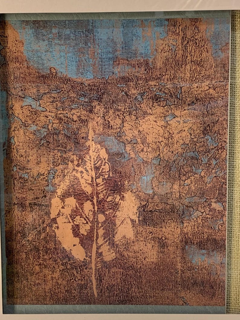 Puede incluir: Impresi&oacute;n art&iacute;stica abstracta con un dise&ntilde;o texturizado en tonos marrones, cobrizos y azules. Una gran huella de hoja est&aacute; centrada en la obra de arte. La impresi&oacute;n est&aacute; enmarcada en un borde blanco.