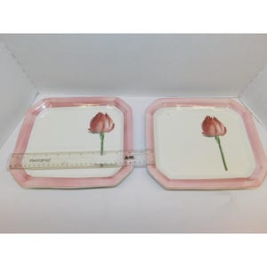 May include: Two square plates with a pink border and a white centre. Each plate features a red tulip illustration. The plates are made of a shatterproof material.