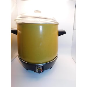 May include: A vintage electric slow cooker with a yellow enamel pot, black handles, and a clear glass lid. The cooker sits on a black base with a temperature control dial. A classic kitchen appliance.