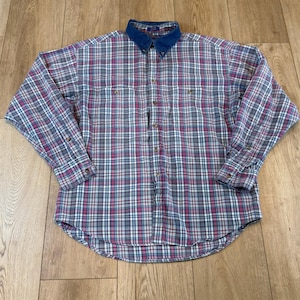 Könnte beinhalten: Ein langärmeliges kariertes Hemd mit einem Jeanskragen. Das Hemd hat ein Muster aus roten, weißen und blauen Karos auf grauem Hintergrund. Es hat zwei Brusttaschen und geknöpfte Manschetten.
