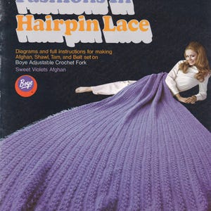 May include: Vintage leaflet titled "Fashions In Hairpin Lace" featuring instructions for making an afghan, shawl, tam, and belt. The cover shows a woman draped in a large, lavender hairpin lace shawl with fringe. The Boye brand logo is visible.