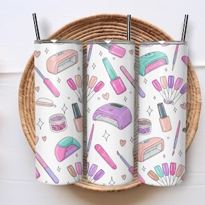 May include: Three white insulated tumblers with black straws, decorated with a repeating pattern of nail art tools, nail polish, and nail polish dryers in pink, purple, and teal. The tumblers are set on a woven basket.