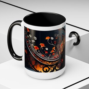 May include: A white ceramic mug with a black interior and handle, featuring a wrap-around graphic design of stylised orange and white flowers on thin, dark, curved stems against a deep black background with intricate, warm-toned circular patterns.