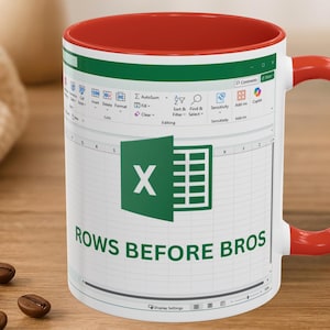 May include: White ceramic mug with a red interior and handle. The mug features a green and white Excel spreadsheet design with the Excel logo and the text "ROWS BEFORE BROS". Coffee beans are visible in the foreground.