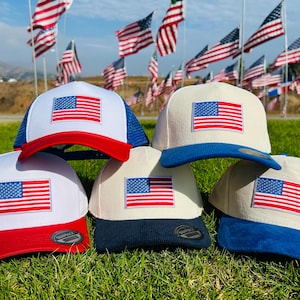 May include: A collection of six baseball caps with the American flag prominently displayed. The caps feature a variety of color combinations, including red, white, and blue, and are set against a backdrop of waving American flags.