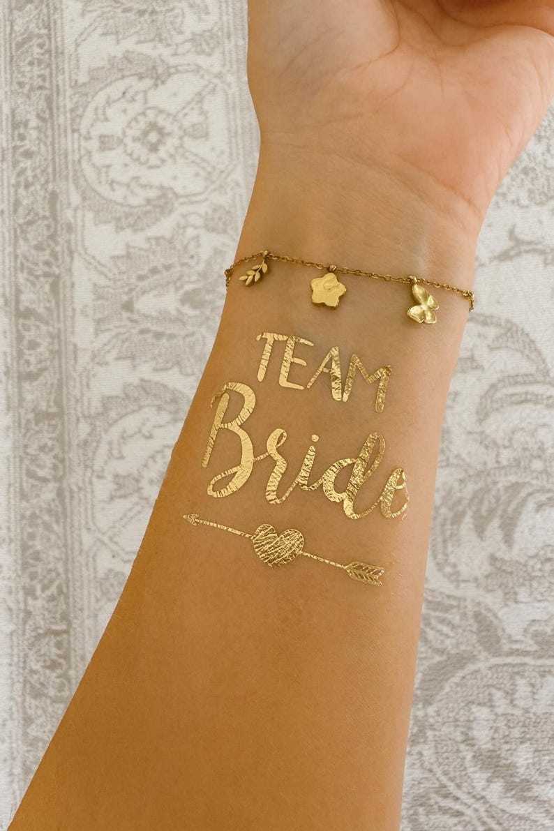 Goldene Team Bride und Bride Tattoos, Tattoos für Junggesellinnenabschied, Bachelorette Party und Hochzeit. Perfekte Accessoires für Braut und Team, glänzende goldene Tattoos für Fotoshooting, Partydeko und Brautparty. Einfache Anwendung, hautfreundlich und wasserfest – ideal als JGA Accessoires, Bridal Shower Tattoo Sticker, Hochzeitsdeko oder Geschenkidee für die Braut und ihre Mädels. JGA Zubehör, Klebetattoos