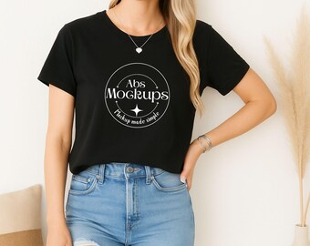 Puede incluir: Una camiseta negra de cuello redondo con el texto "Abs Mockups" en un diseño circular. La camiseta se usa con vaqueros de mezclilla azul claro. El diseño incluye las palabras "Mockup made simple".