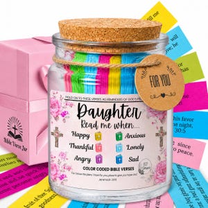 May include: A glass jar with a cork lid, filled with colorful Bible verses. The jar is labeled "Daughter, Read me when..." and includes a "For You" tag. A pink gift box is in the background.