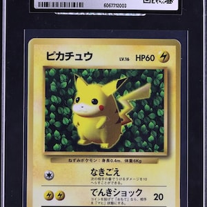 Può includere: Carta Pokémon Pikachu del 1996, serie giapponese CoroCoro Comic Promo, classificata. Presenta un'illustrazione di Pikachu giallo con testo giapponese, racchiusa in un supporto nero con etichetta CGC Certified Authentic.