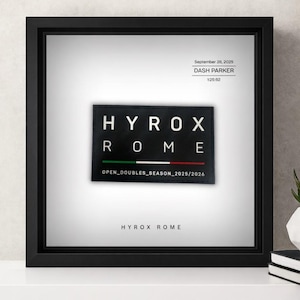 May include: Black framed artwork with the text "HYROX ROME". The artwork displays the date "September 28, 2025", the name "DASH PARKER" and a time of 1:25:52. The text "OPEN_DOUBLES_SEASON_2025/2026" is also visible.