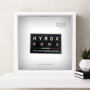 May include: A framed print with the words "HYROX ROME" in white on a black rectangle. The print also displays the date "September 28, 2025" and the name "DASH PARKER". The bottom of the print reads "OPEN_DOUBLES_SEASON_2025/2026".