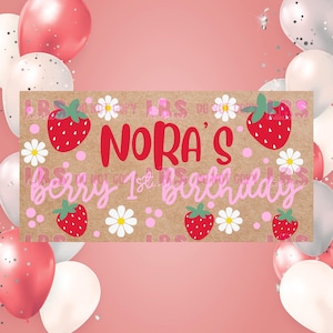 May include: A banner with the text "Nora's berry 1st birthday" in red and pink, decorated with strawberries and daisies. The banner is on a brown background, surrounded by pink and white balloons.