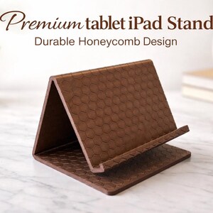 Könnte beinhalten: Ein brauner Tablet-Ständer mit Wabenmuster. Der Ständer ist abgewinkelt und hat einen Schlitz zur Aufnahme eines Tablets. Der Text lautet "Premium tablet iPad Stand" und "Durable Honeycomb Design".