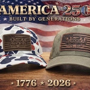 May include: Two trucker hats featuring leather patches with the text America 250 1776-2026. The left hat has a white, red, and blue camouflage pattern with a white mesh back. The right hat is olive green with a subtle star pattern and a tan mesh back.