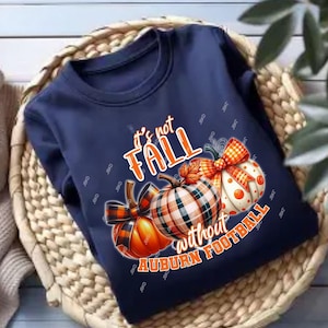 May include: Navy blue sweatshirt with a pumpkin design. The text reads "It's not FALL without AUBURN FOOTBALL". The pumpkins are orange, white, and plaid, with orange and black plaid bows.