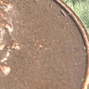 以下が含まれることがあります： 下部に1972年と刻印された銅色の米国1セント硬貨。硬貨の上端にはTRUSTという文字の一部が見え、質感のある金属表面と、縁に沿って盛り上がった円形のリムが特徴です。