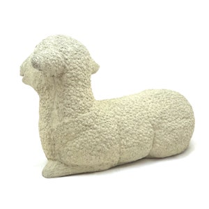 May include: A white ceramic sculpture of a lying lamb. The lamb has a textured surface that resembles wool.