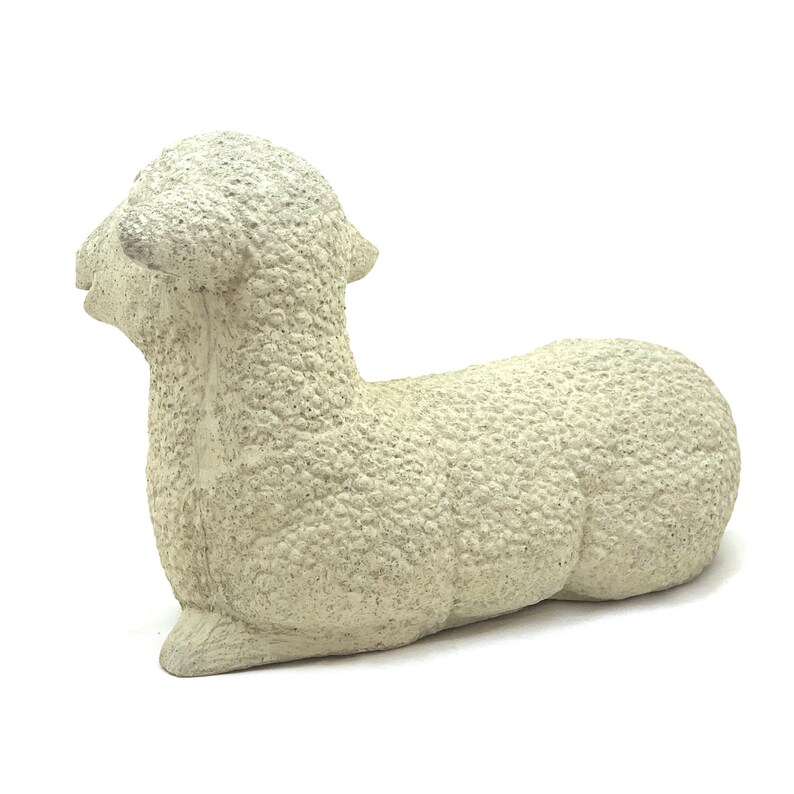 May include: A white ceramic sculpture of a lying lamb. The lamb has a textured surface that resembles wool.