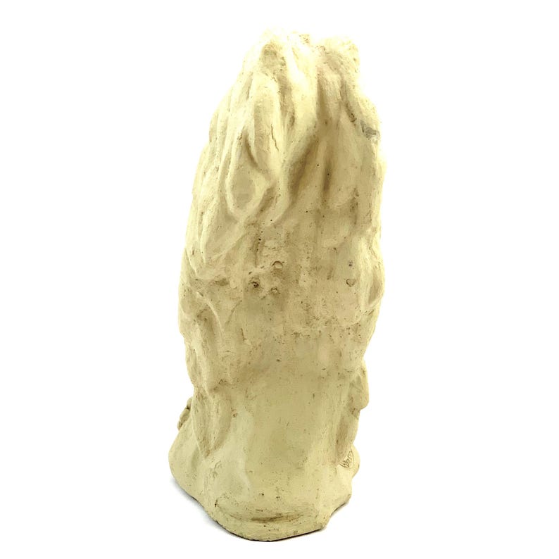 May include: A cream-colored, textured sculpture of an owl viewed from the back. The surface features carved, overlapping feather patterns that create a layered, dimensional appearance across the entire body of the bird figure.