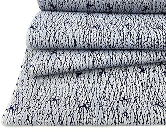 May include: A stack of fabric featuring a repeating pattern of dark blue lines and shapes on a light grey background. The fabric is folded and rolled, displaying the design. Suitable for sewing projects.