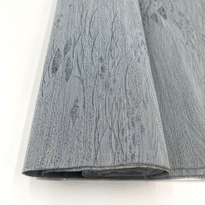 May include: A roll of blue and white patterned tissue paper with a wood grain design. The tissue paper is rolled up and the end is visible.