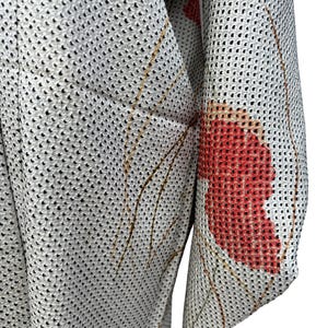 May include: A white kimono with a red floral pattern. The kimono is made of a lightweight, breathable fabric and has a mesh-like texture.