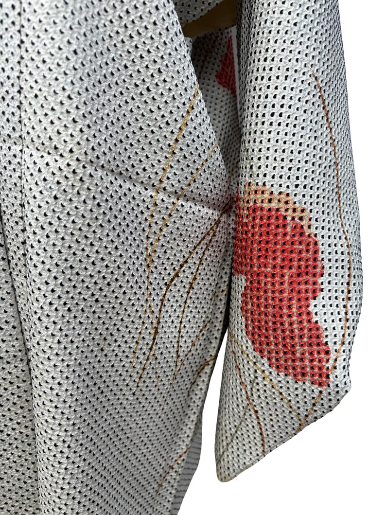 May include: A white kimono with a red floral pattern. The kimono is made of a lightweight, breathable fabric and has a mesh-like texture.