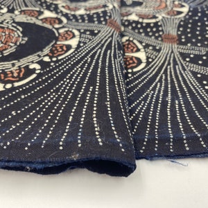 Puede incluir: Primer plano de una tela azul oscuro con un dise&ntilde;o estampado en blanco y marr&oacute;n. La tela tiene un patr&oacute;n repetitivo de c&iacute;rculos con puntos blancos y l&iacute;neas que irradian hacia afuera.