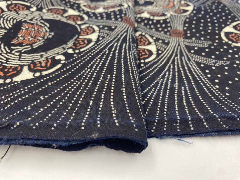Puede incluir: Primer plano de una tela azul oscuro con un dise&ntilde;o estampado en blanco y marr&oacute;n. La tela tiene un patr&oacute;n repetitivo de c&iacute;rculos con puntos blancos y l&iacute;neas que irradian hacia afuera.