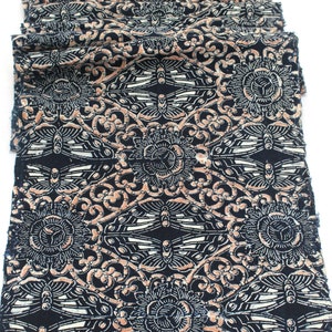 May include: Folded fabric with a repeating pattern of stylized butterflies, flowers, and swirling lines in black, white, and peach. The fabric is likely cotton or a similar material, and the design is printed on the surface.