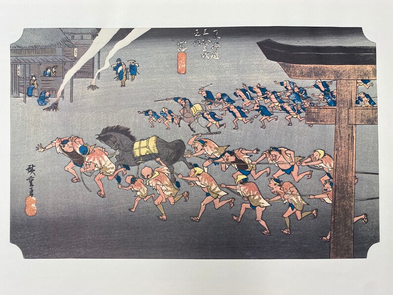 May include: Japanese woodblock print showing a nighttime scene with figures pulling a horse. The print features a building on the left, a large gate on the right, and numerous figures running with ropes. The colour palette includes shades of blue, grey, and brown.