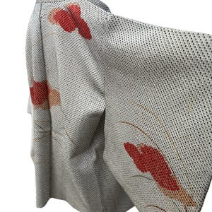 May include: A white Japanese kimono with a red and orange floral pattern. The kimono is made of a lightweight fabric and has a traditional design.
